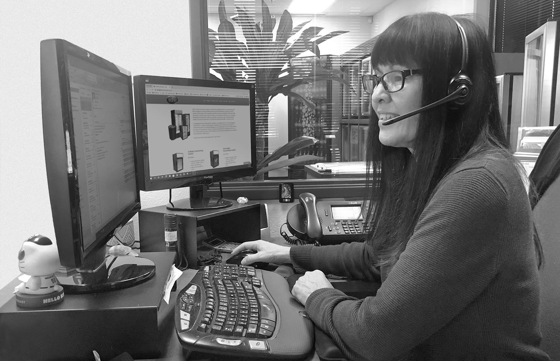 Worker doing sales support using headphones and while look at two computer monitors
